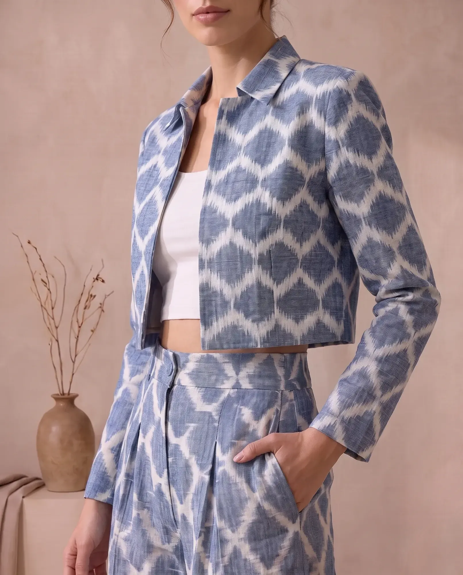 Close-up of the cropped ikat jacket's collar and long sleeve, with the pleated trouser waist and side pocket