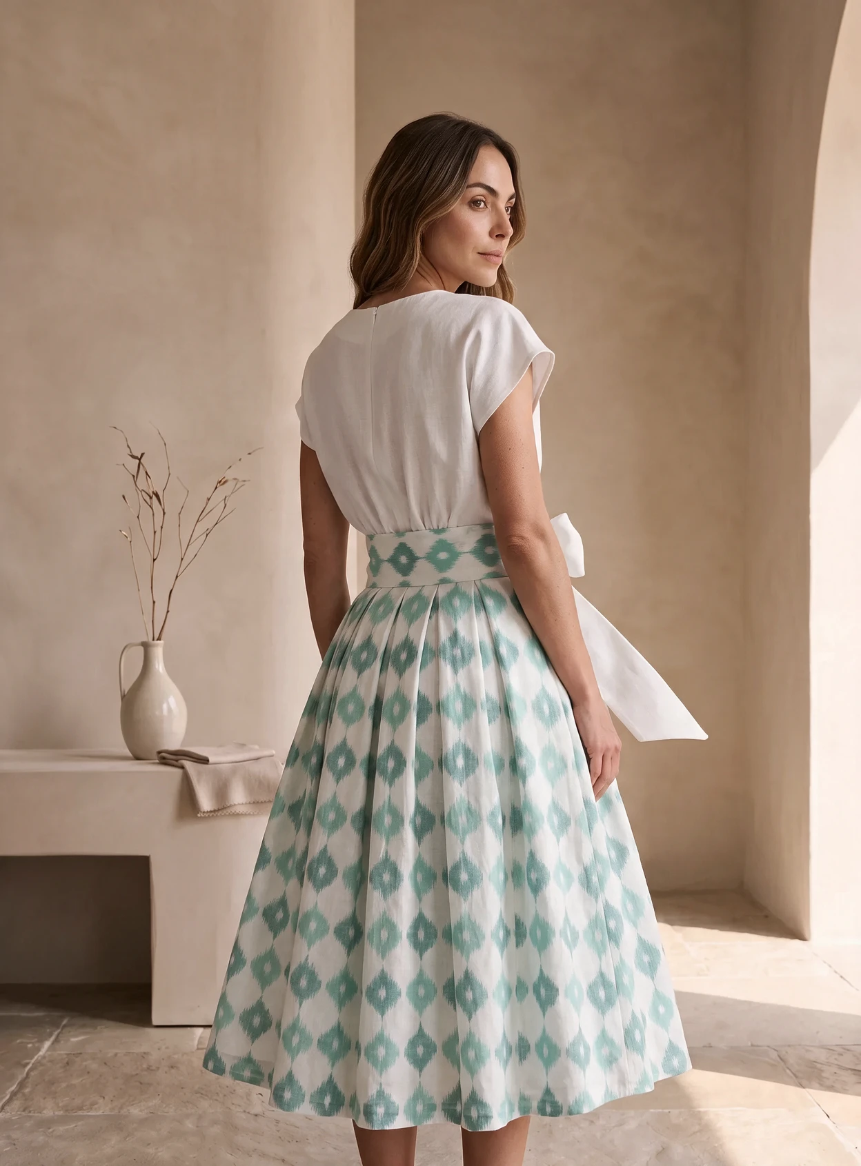 Back three-quarter view of the mint ikat skirt's box pleats and sash ends